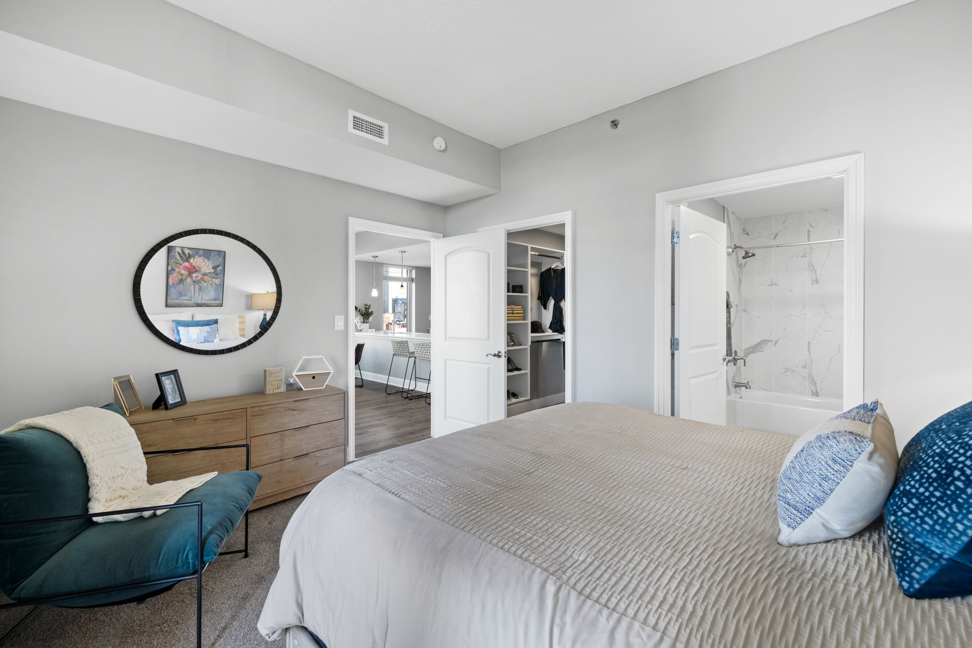 A bedroom with a bed , dresser , chair and mirror.