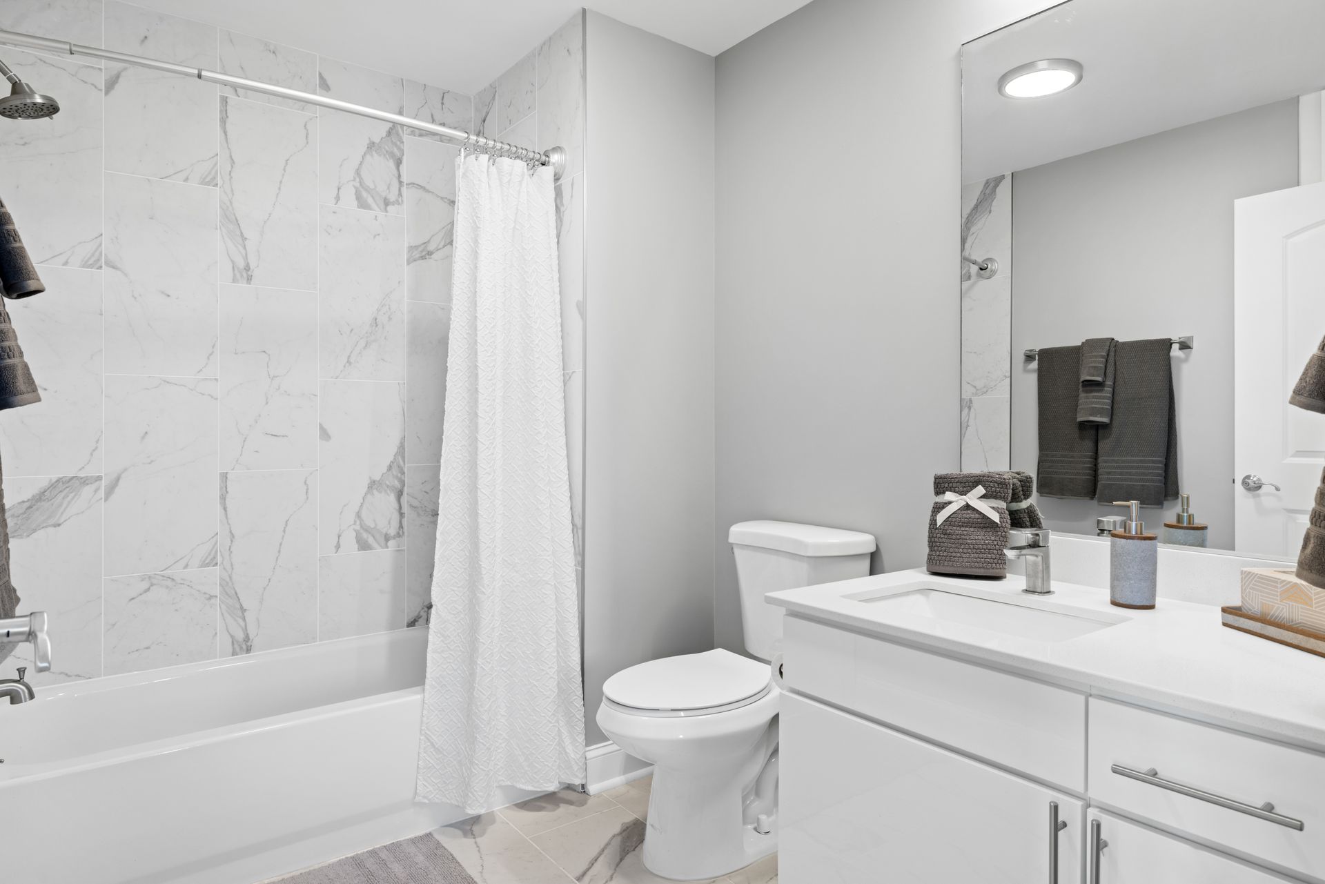 A bathroom with a toilet , sink , shower and mirror.