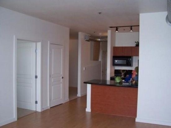 Empty modern apartment interior with white walls, hallway, and kitchen island with dark countertop