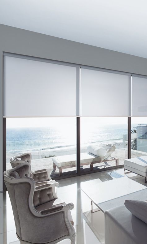 Bright ocean-view lounge with white furniture and large windows overlooking a balcony and sea. — Blinds & Curtains in Townsville, QLD