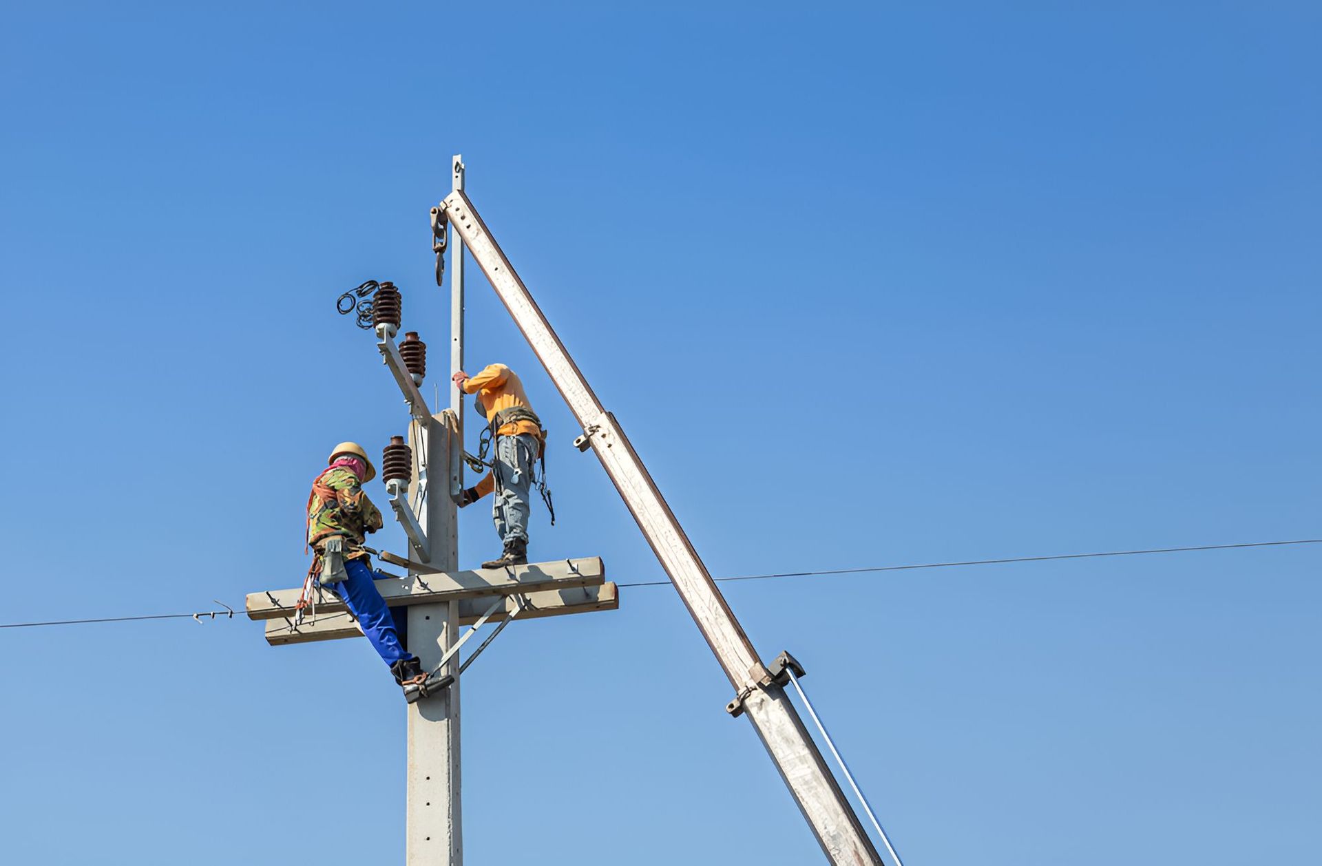 Two Men Are Working On A Powerline With Blue Sky — Entire Power Solutions In Merewether, NSW