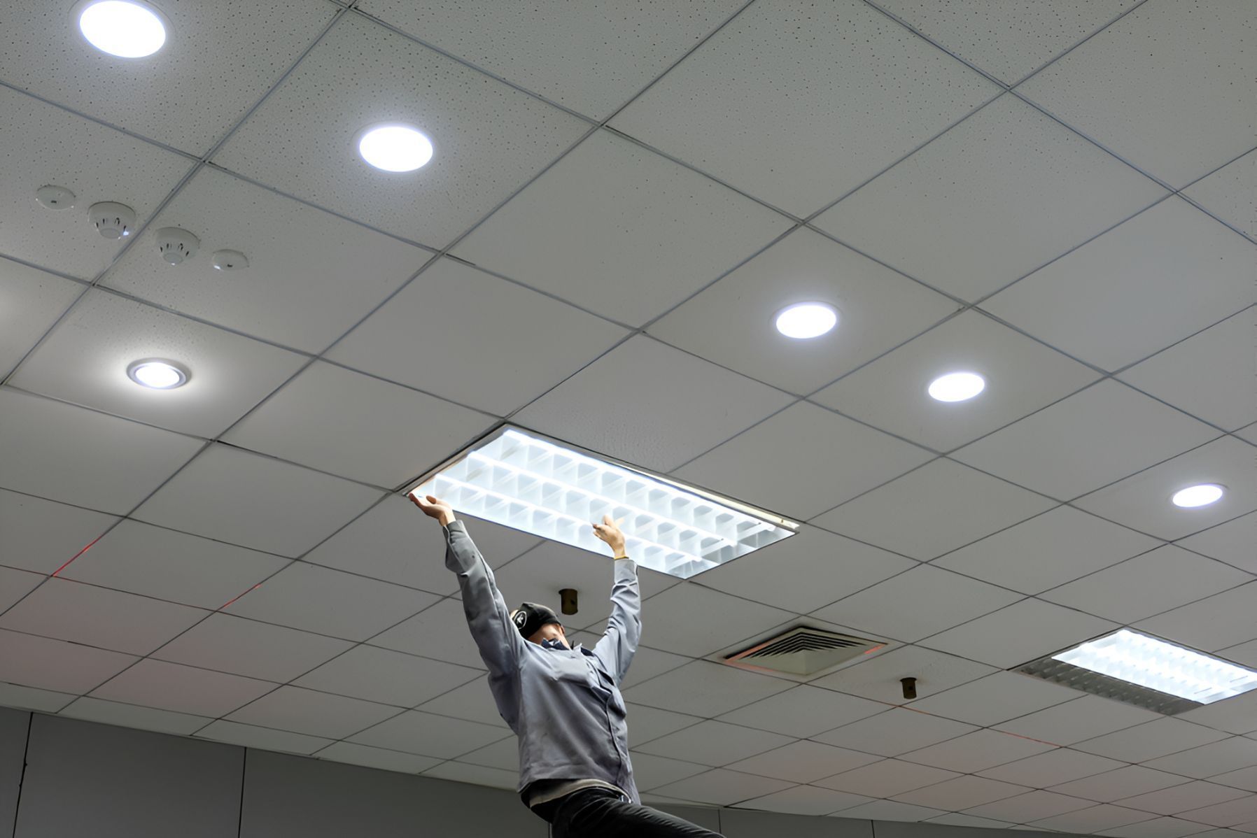 A Man Is Installing A Light In The Ceiling — Entire Power Solutions In Merewether, NSW