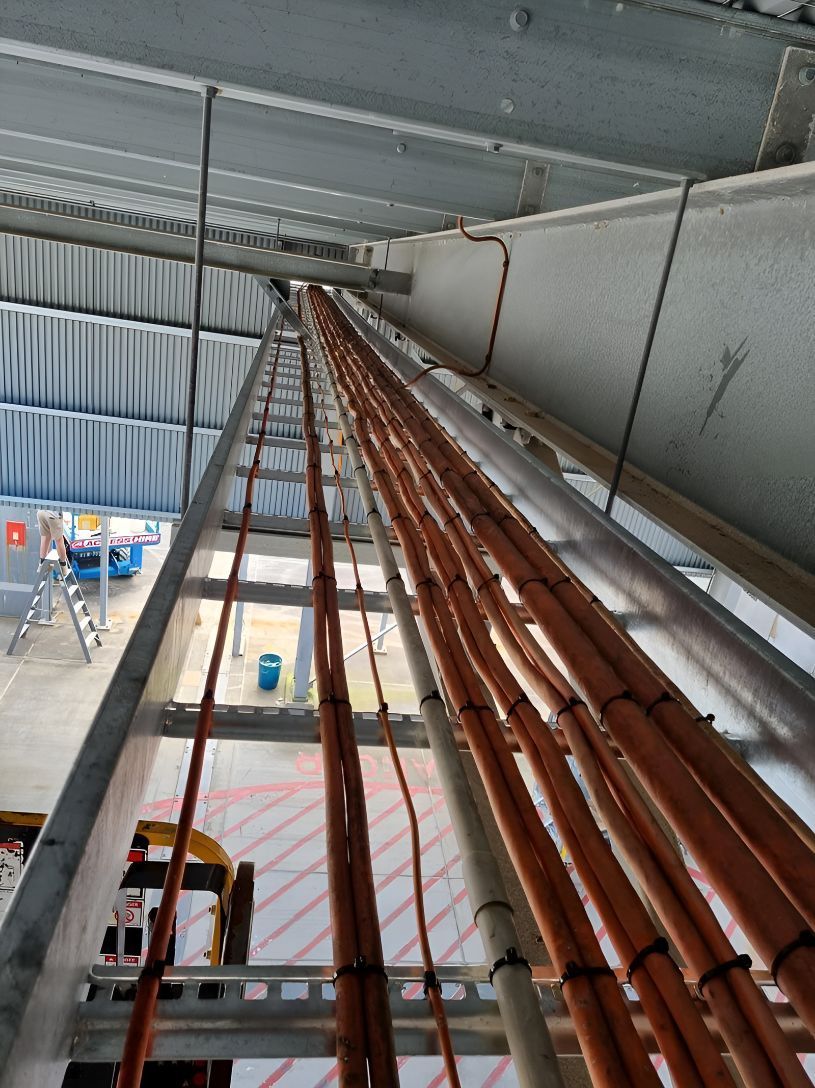 A Ladder Is Hanging From The Ceiling Next To A Bunch Of Pipes — Entire Power Solutions In Ashtonfield, NSW