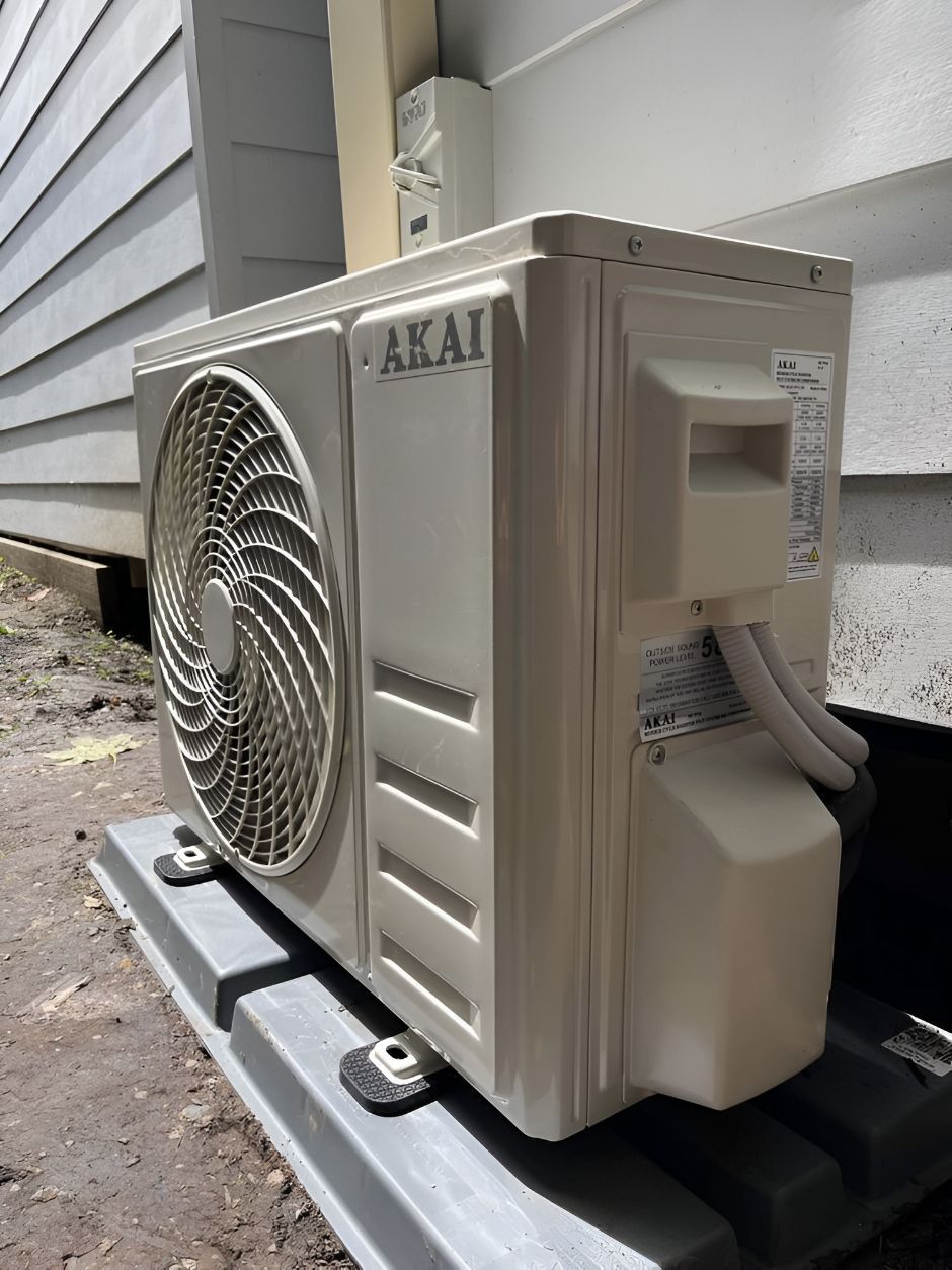 A White Air Conditioner Is Sitting Outside Of A House — Entire Power Solutions In Belmont, NSW