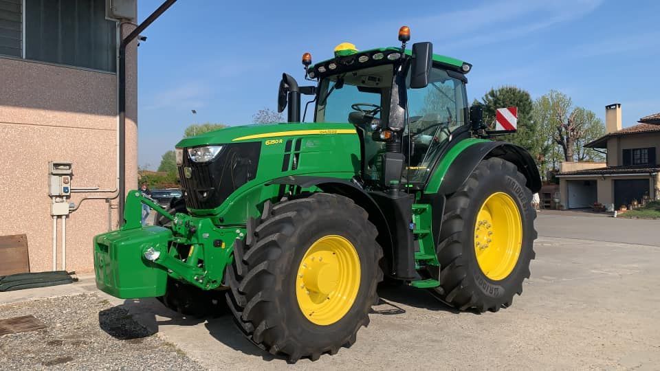 Un trattore John Deere verde e giallo è parcheggiato davanti a un edificio.