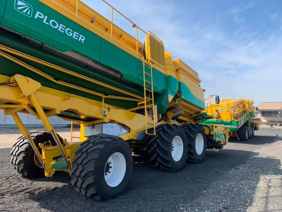 Un trattore ploeger giallo e verde è parcheggiato sul ciglio della strada