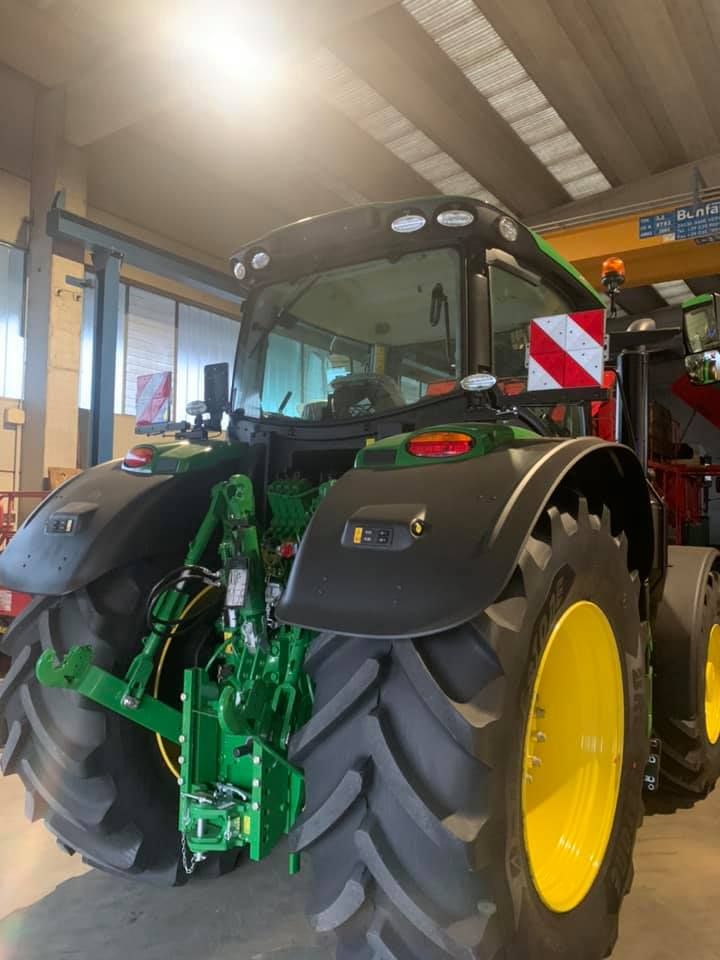 Un trattore John Deere verde e giallo è parcheggiato in un garage