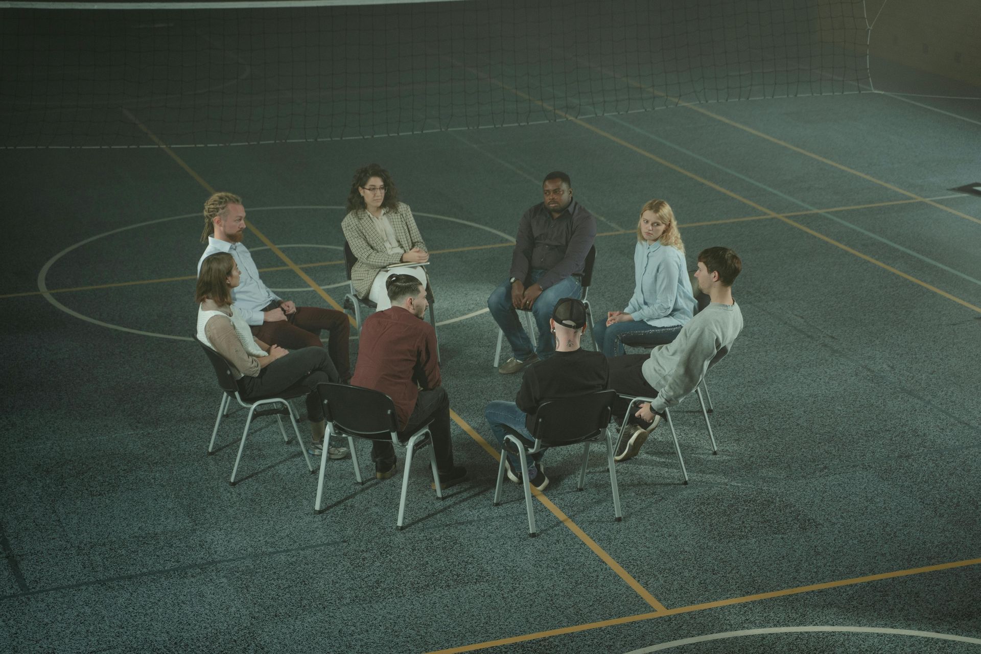 A group of people are sitting in a circle on a basketball court