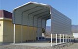 A metal carport is sitting in front of a building.