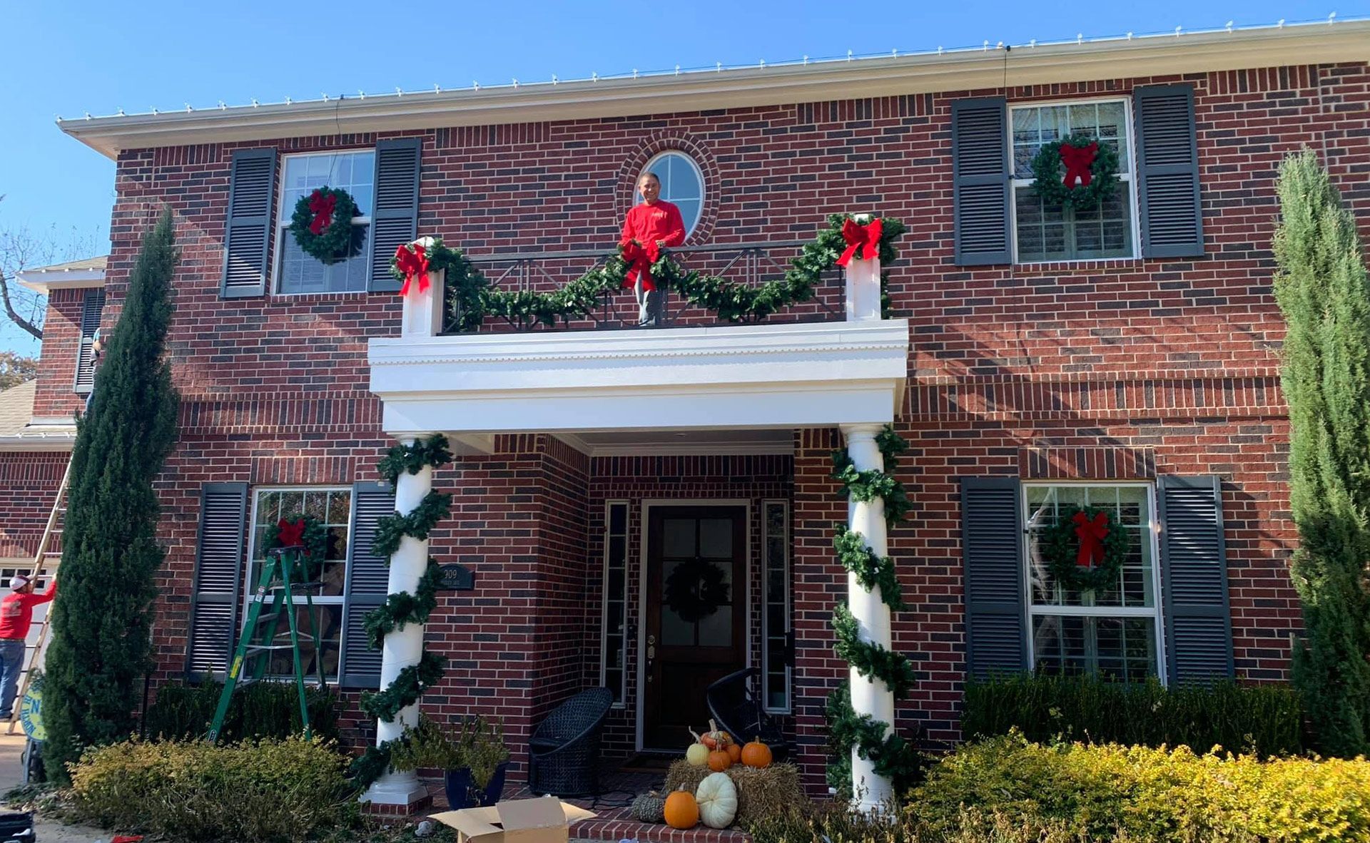 Red brick house decorated for Christmas with wreaths, garland, and bows.