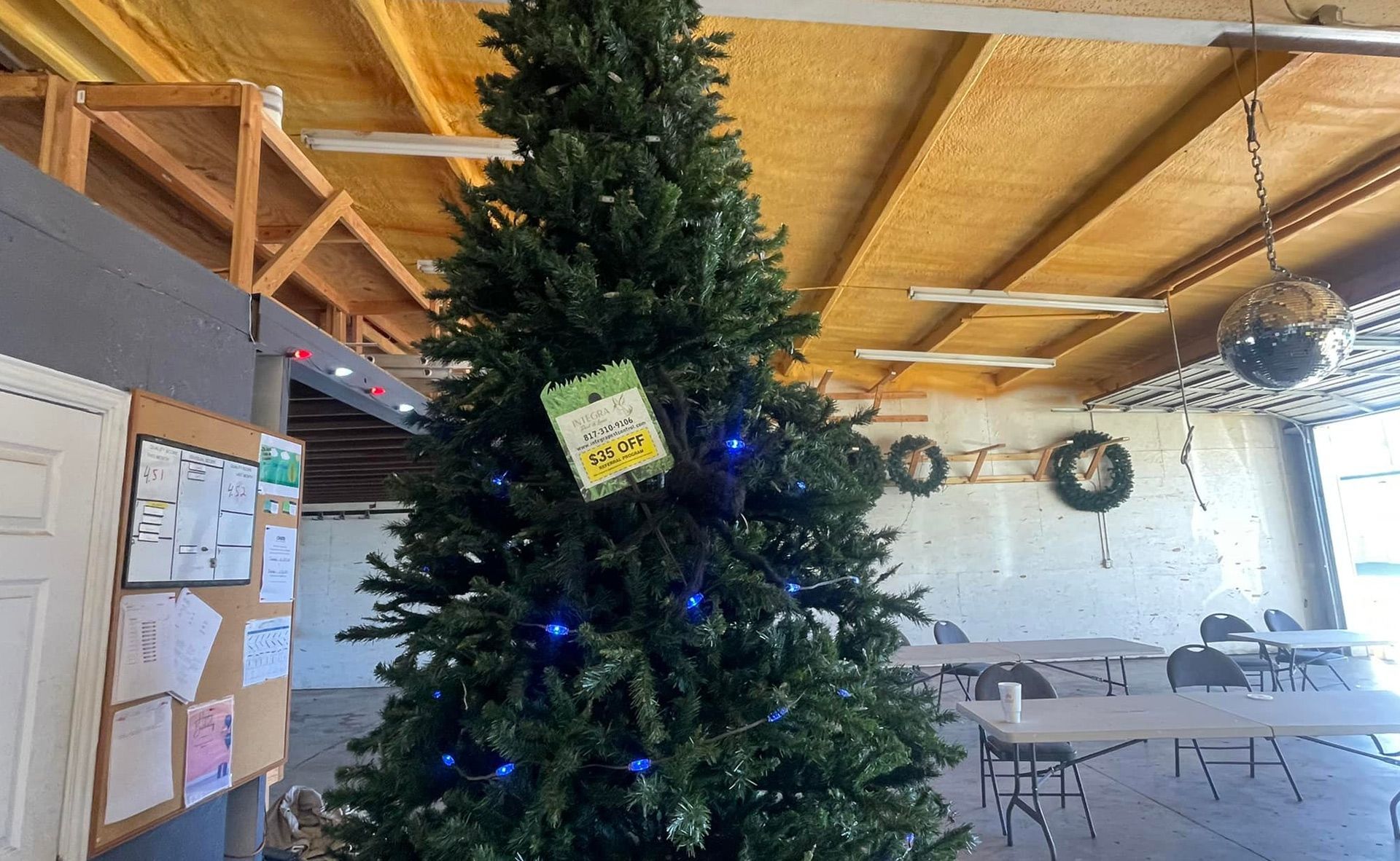 Christmas tree with blue lights in a room with tables and wreaths.