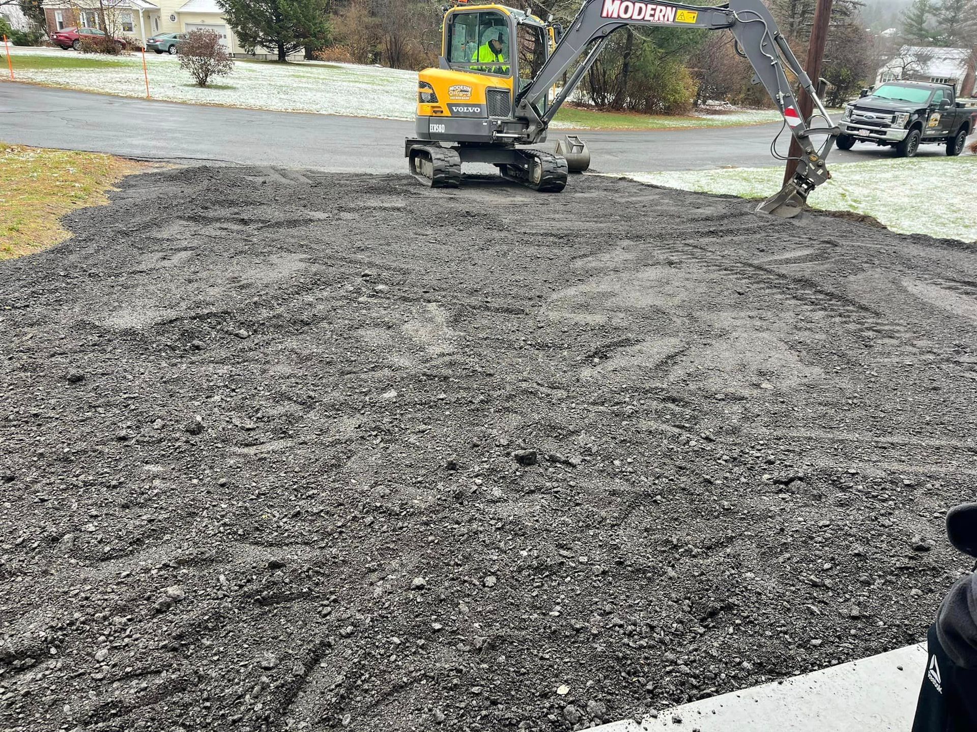 A small excavator is working on a gravel road.