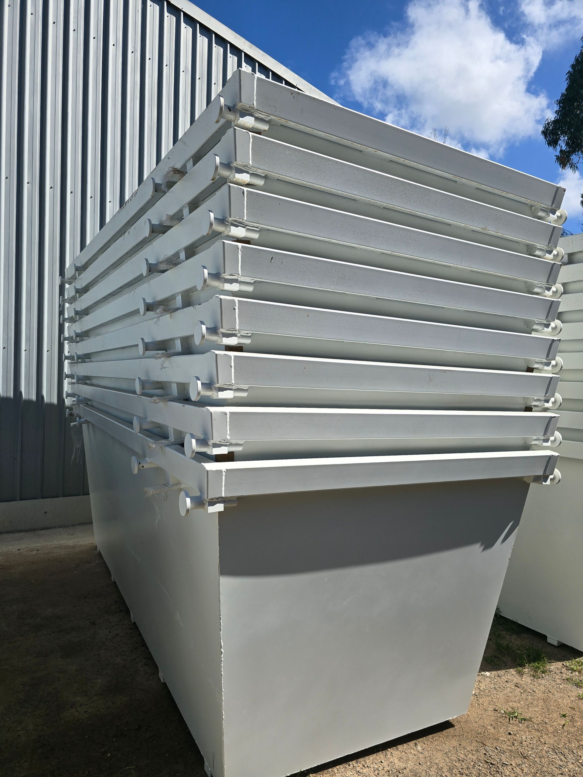 Green Dumpster Overflowing with Cardboard, Drywall, and Debris on A Paved Surface — Coastal Skip Bin Hire In Fraser Coast, QLD