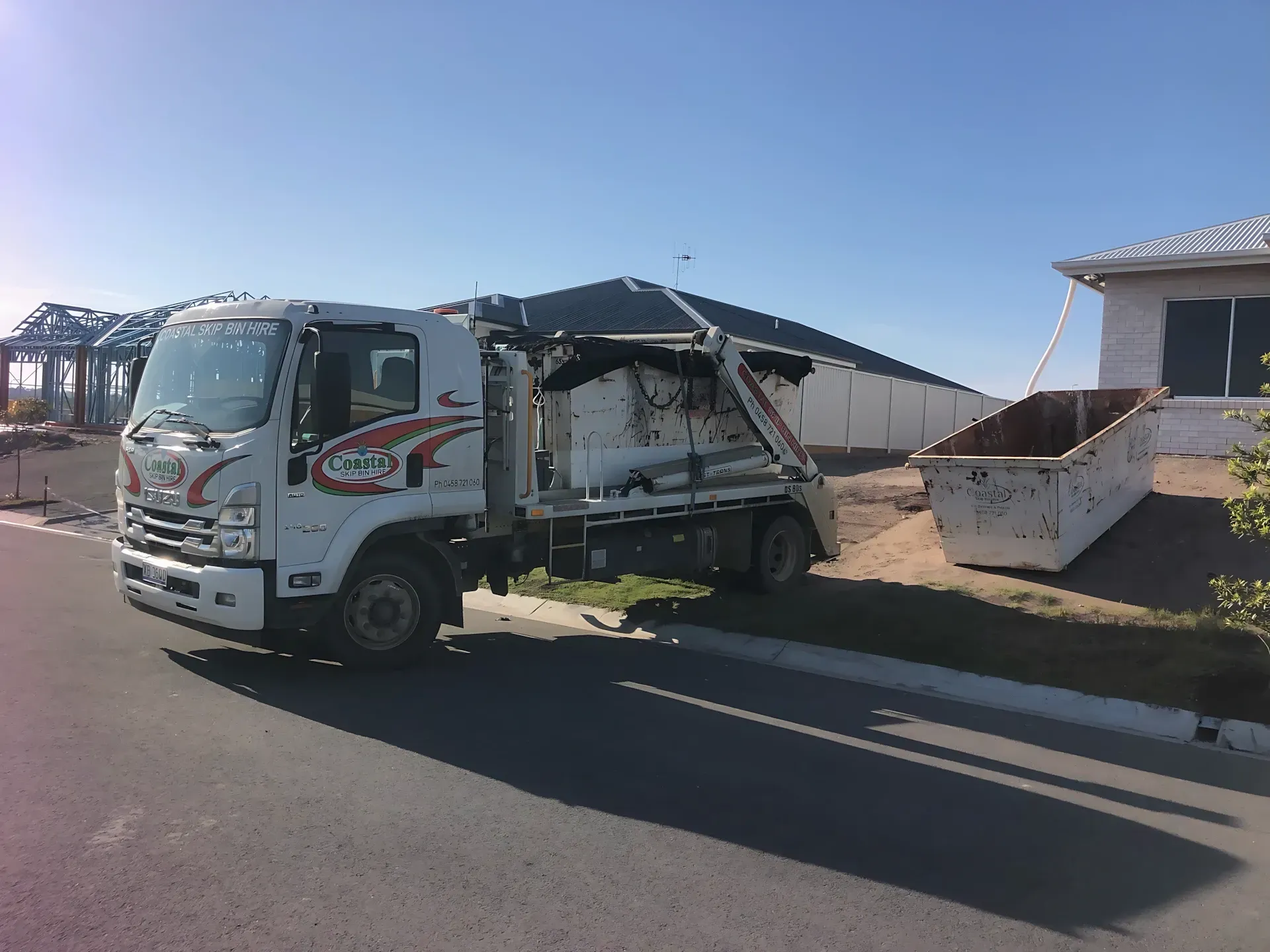 Garbage truck next to a dumpster on a residential street — Coastal Skip Bin Hire In Craignish, QLD