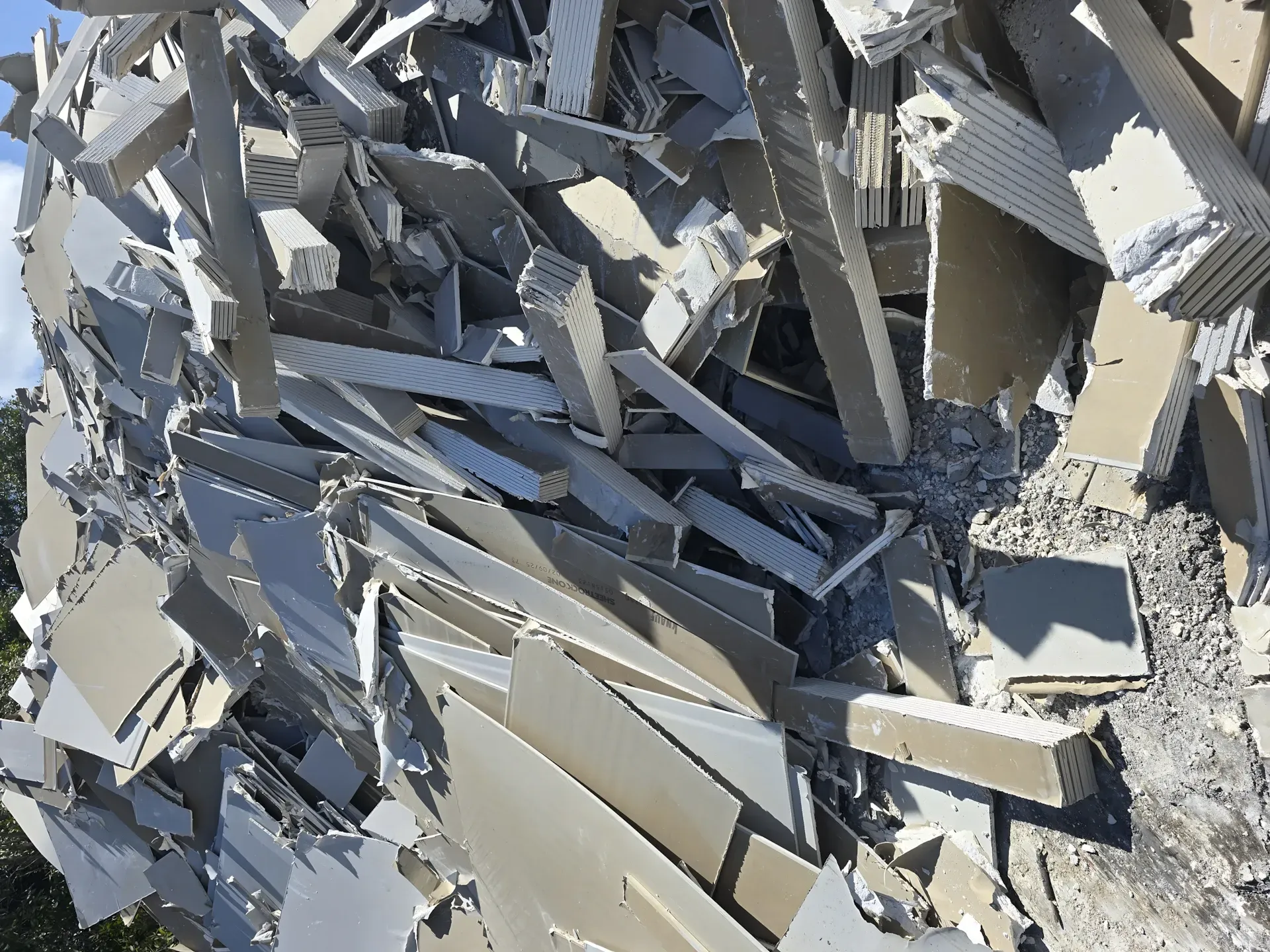 Pile of broken, gray construction materials, likely siding and debris outdoors. — Coastal Skip Bin Hire In Fraser Coast, QLD