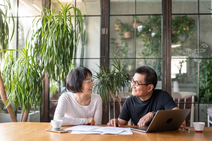 A man and a woman are sitting at a table with a laptop.