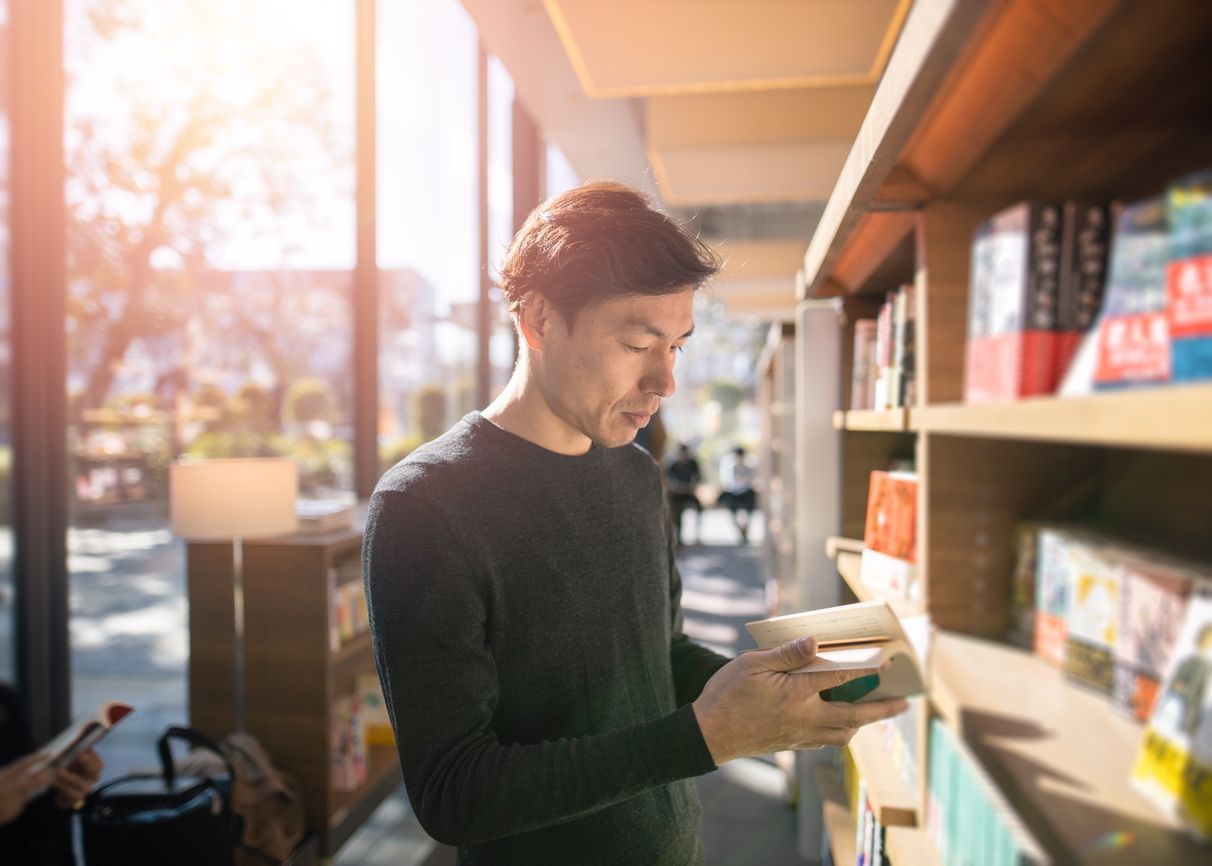 A man is looking at a book in a library.