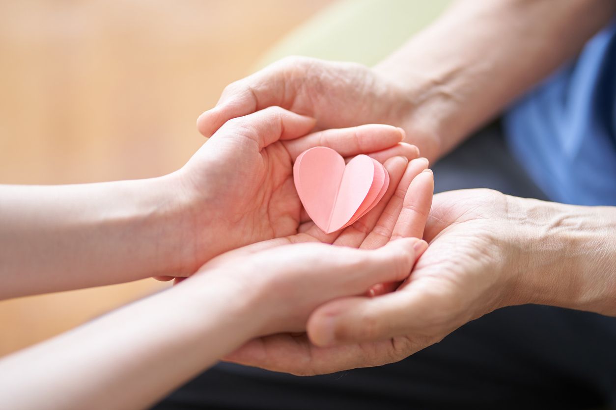 A person is holding a pink heart in their hands.