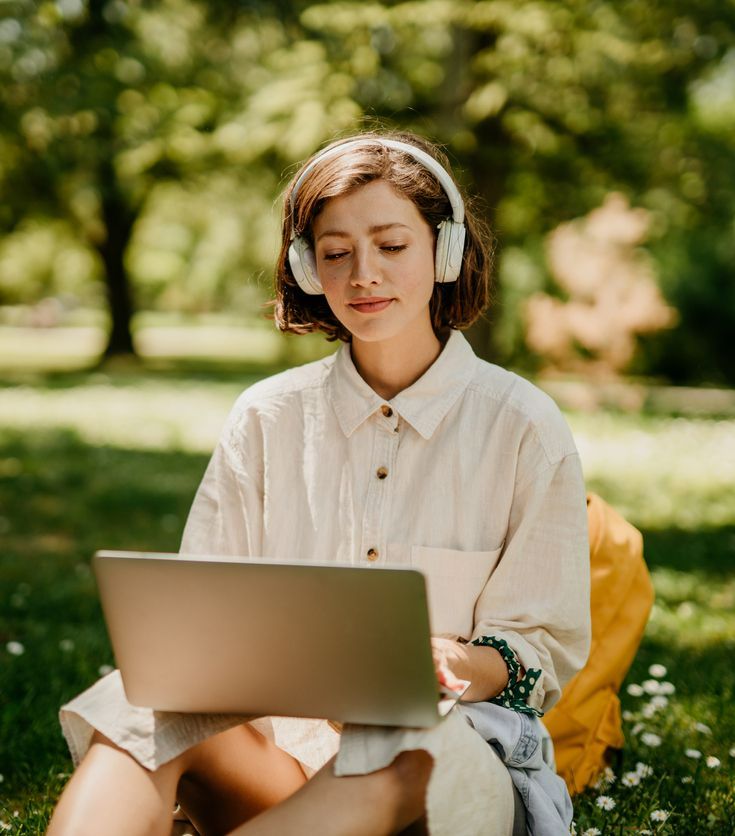 A woman wearing headphones is using a laptop computer.
