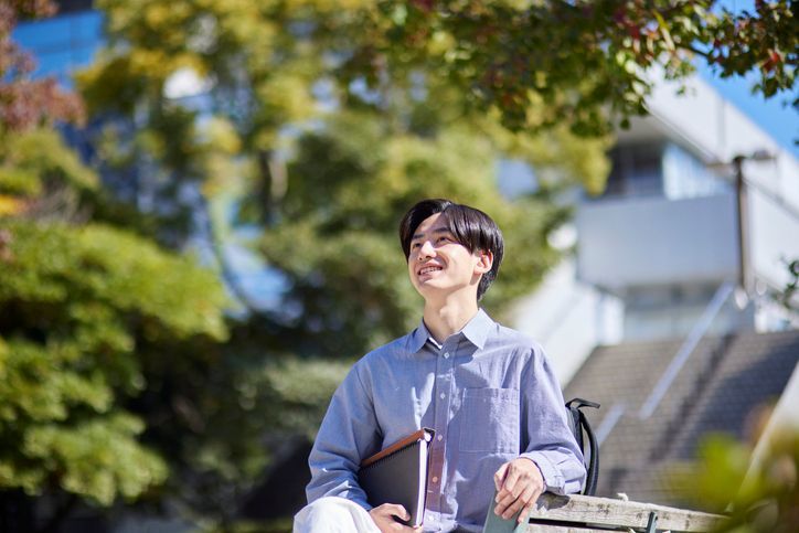 A woman is standing on a balcony reading a book.