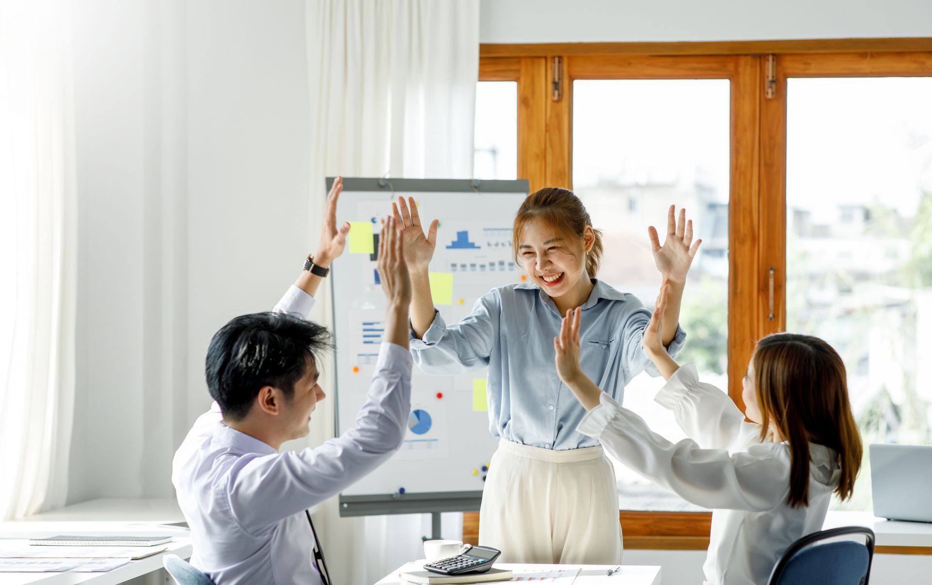 A group of people are giving each other a high five in an office.