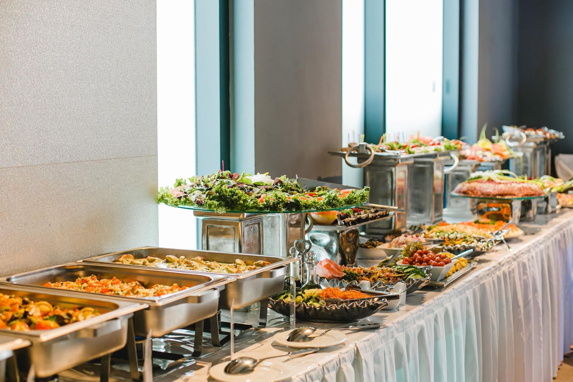 Buffet table with assorted appetizers and salads set up indoors by a window