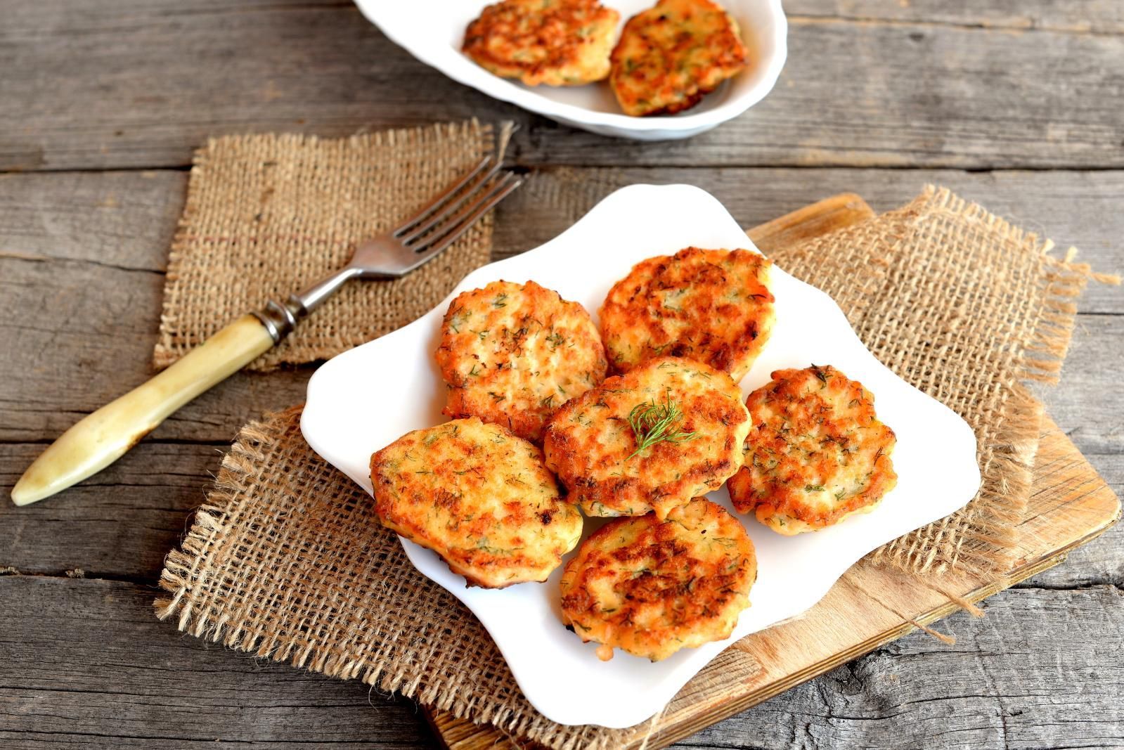 Baked patties on white plates atop burlap mats with a fork on a rustic wooden table