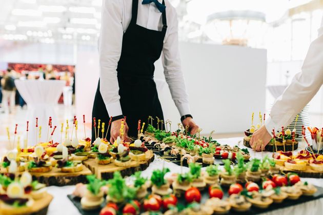Catered buffet table with assorted appetizers and a server arranging the food