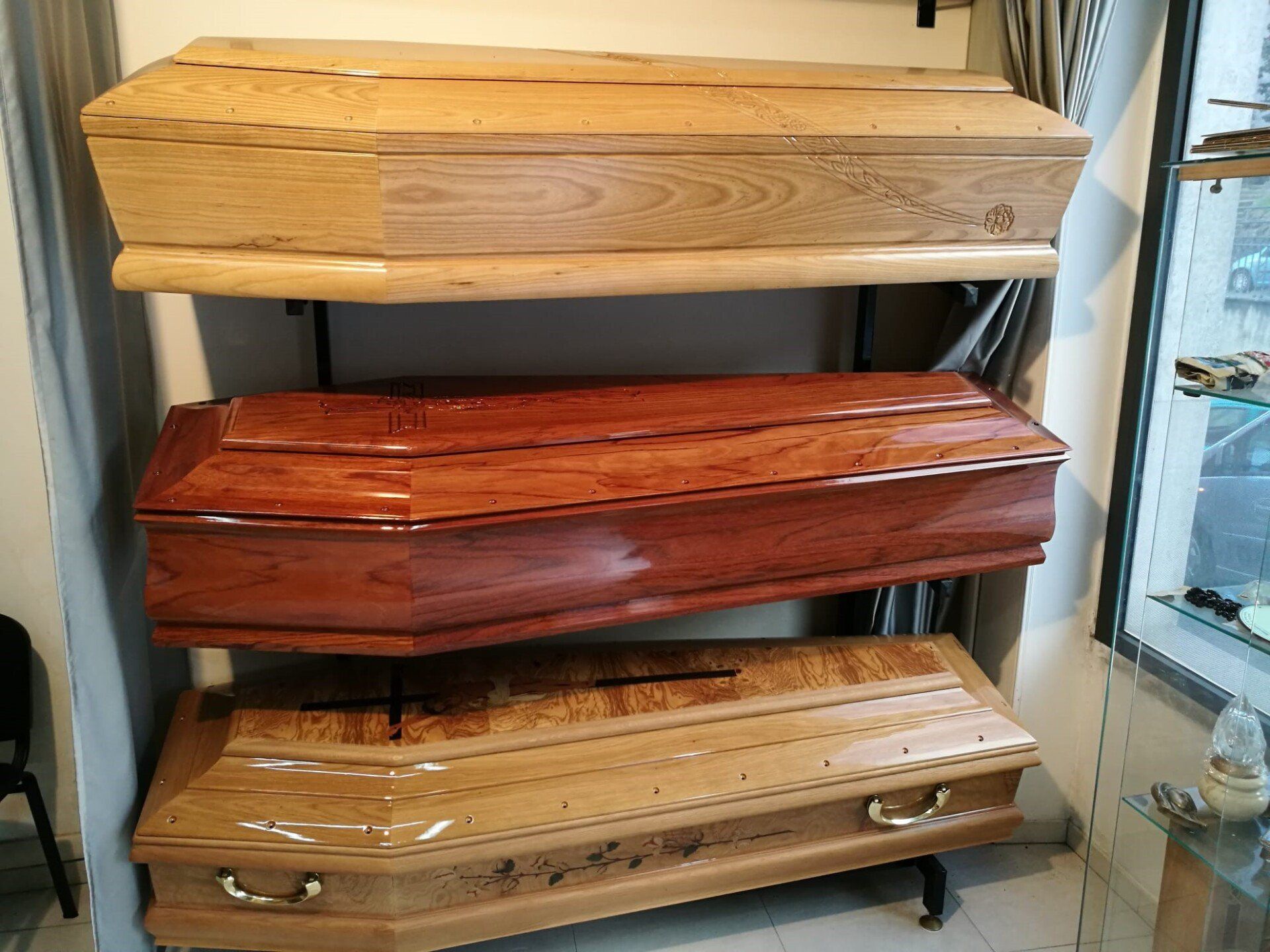 Tre cofanetti di legno esposti sugli scaffali di uno showroom.