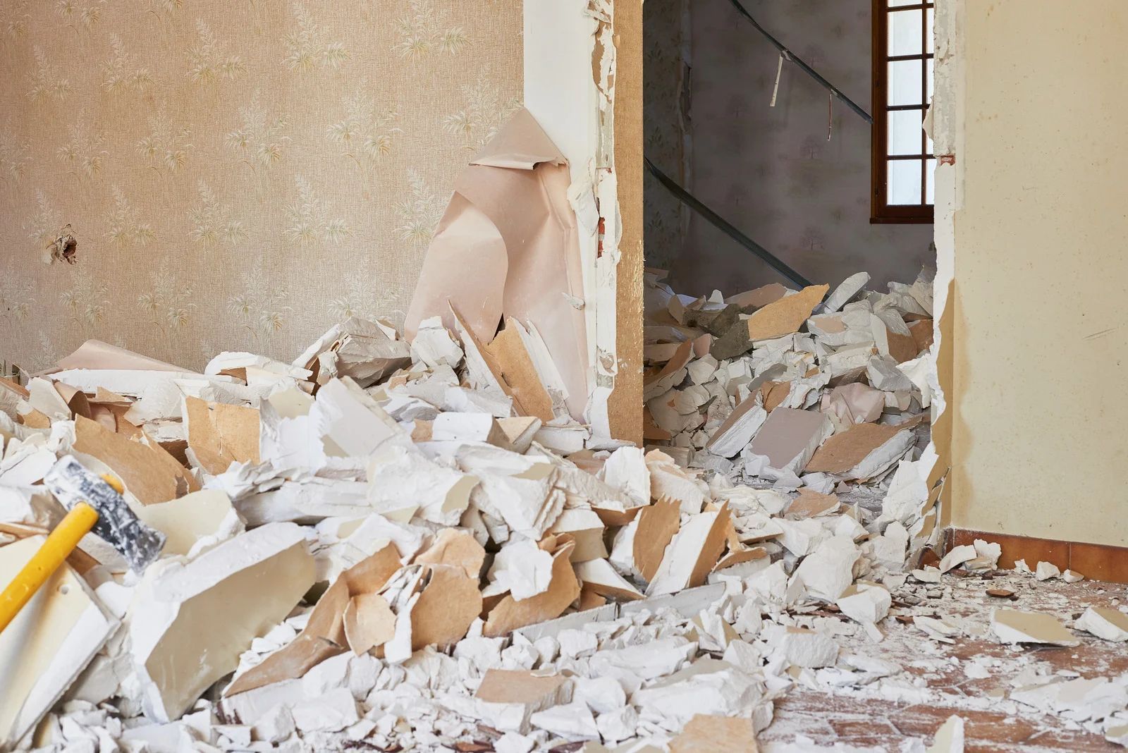 Collapsed interior wall with rubble scattered across a damaged room and doorway