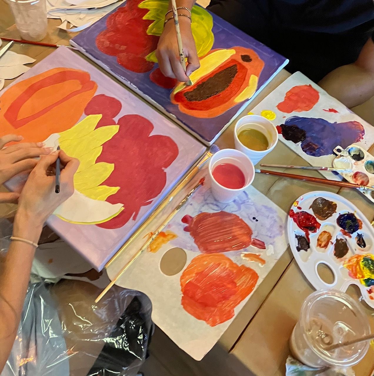 A group of people are painting pumpkins on canvases