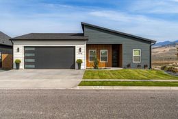 Gray split-level house with two-car garage, driveway, and front lawn under trees