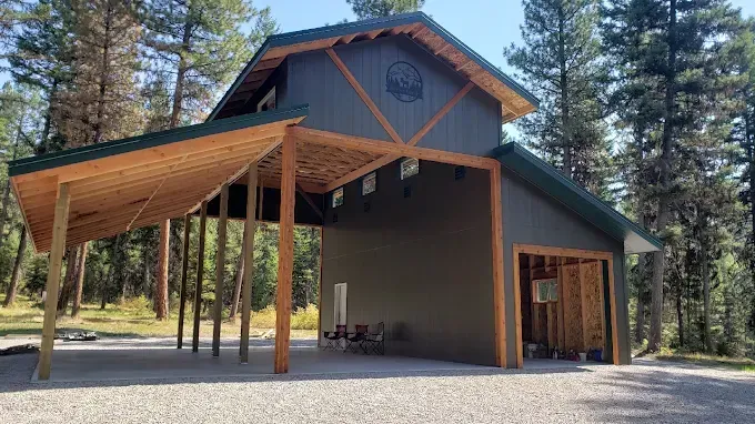 Rustic cabin with a large wooden porch and tall pine trees in a forest clearing