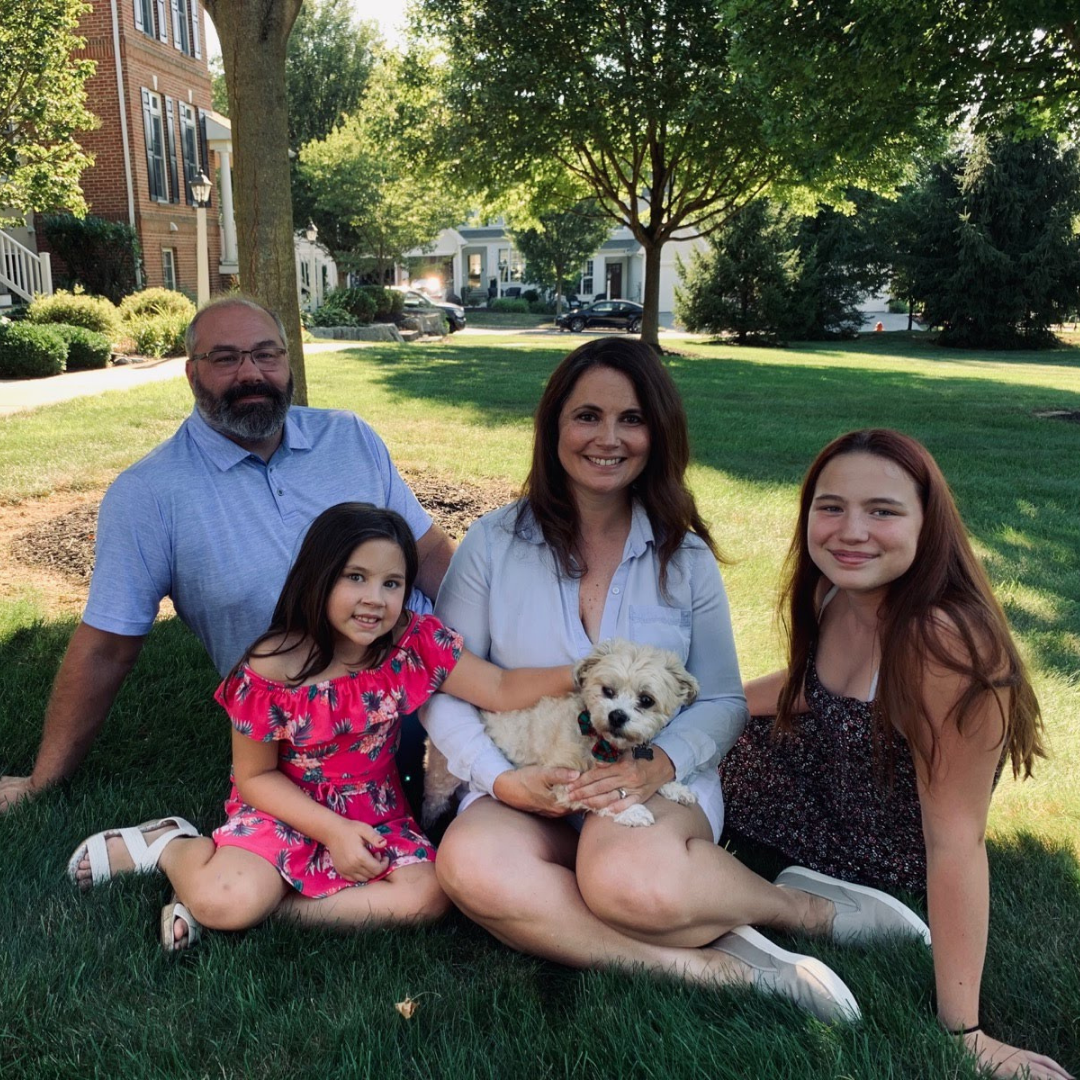 A family sitting on the grass with a dog
