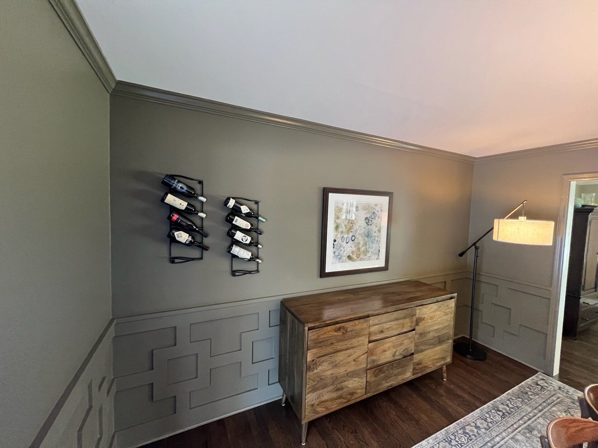 A living room with a dresser and a wine rack on the wall.