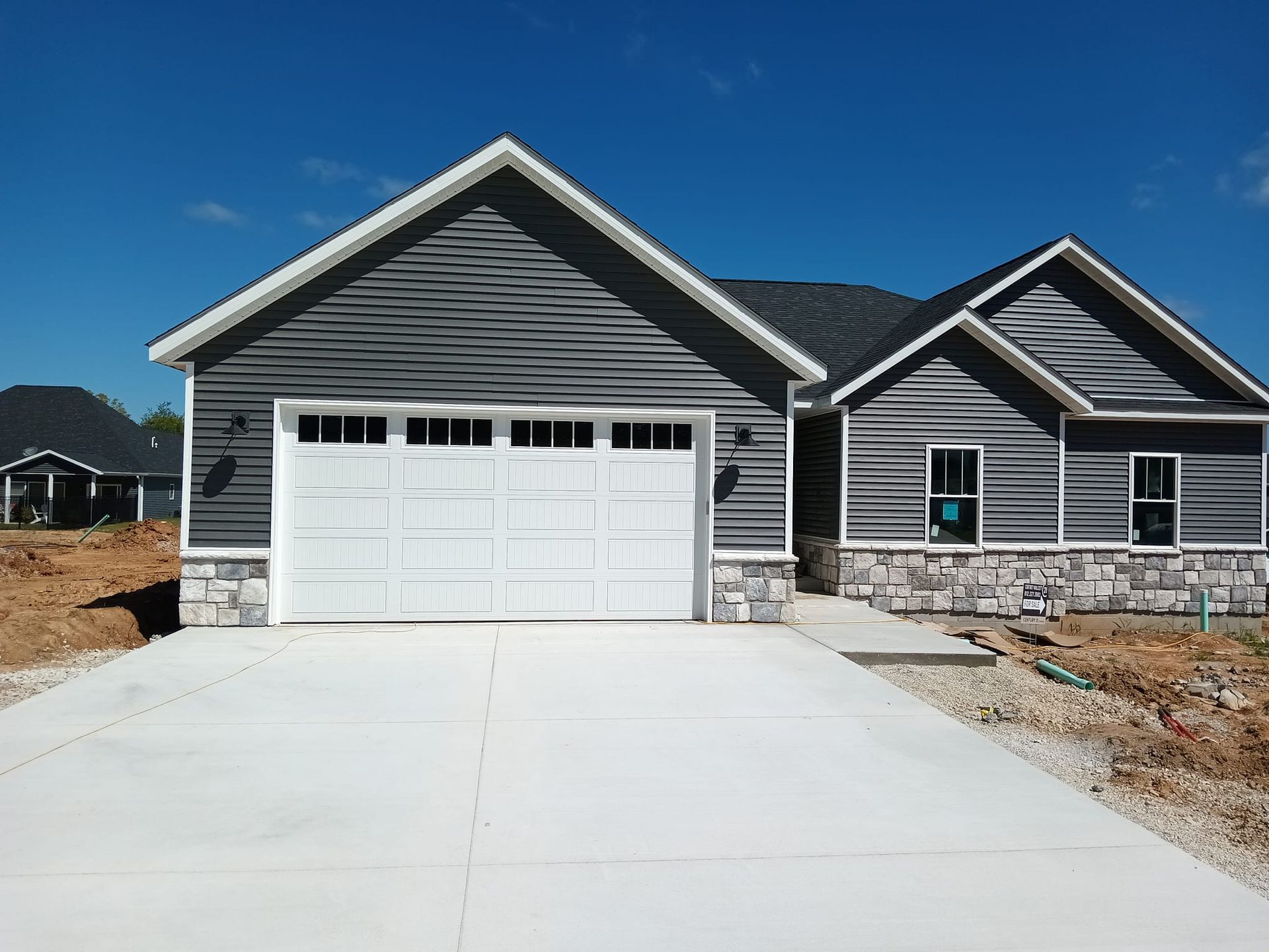 A large house with three garage doors and a weather vane on the roof.