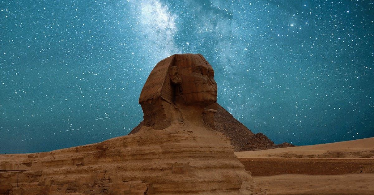 Great Sphinx of Giza under a starry night sky. Sand dunes in foreground.