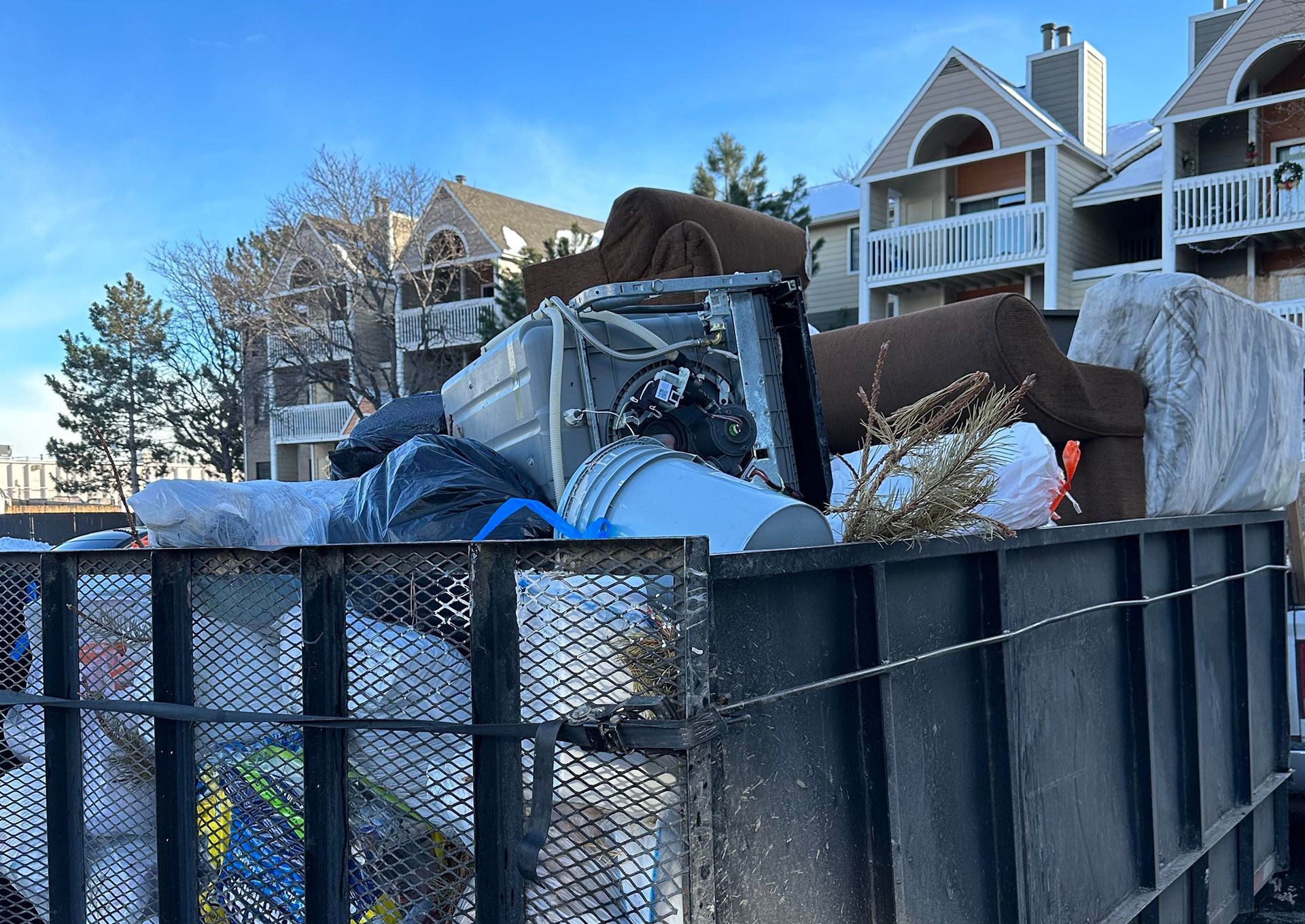 Junk removal trailer loaded with old furniture, mattresses, yard waste, and unwanted household items