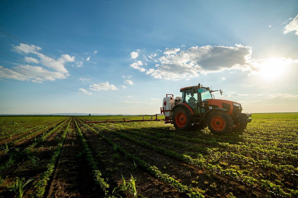 A Tractor is Spraying Fertilizer on a Lush Green Field — Lavington Auto Electrical in Beechworth, VIC
