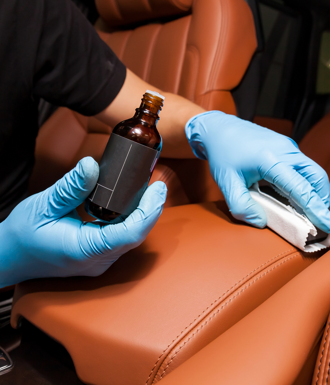 A person wearing blue gloves is holding a bottle of liquid