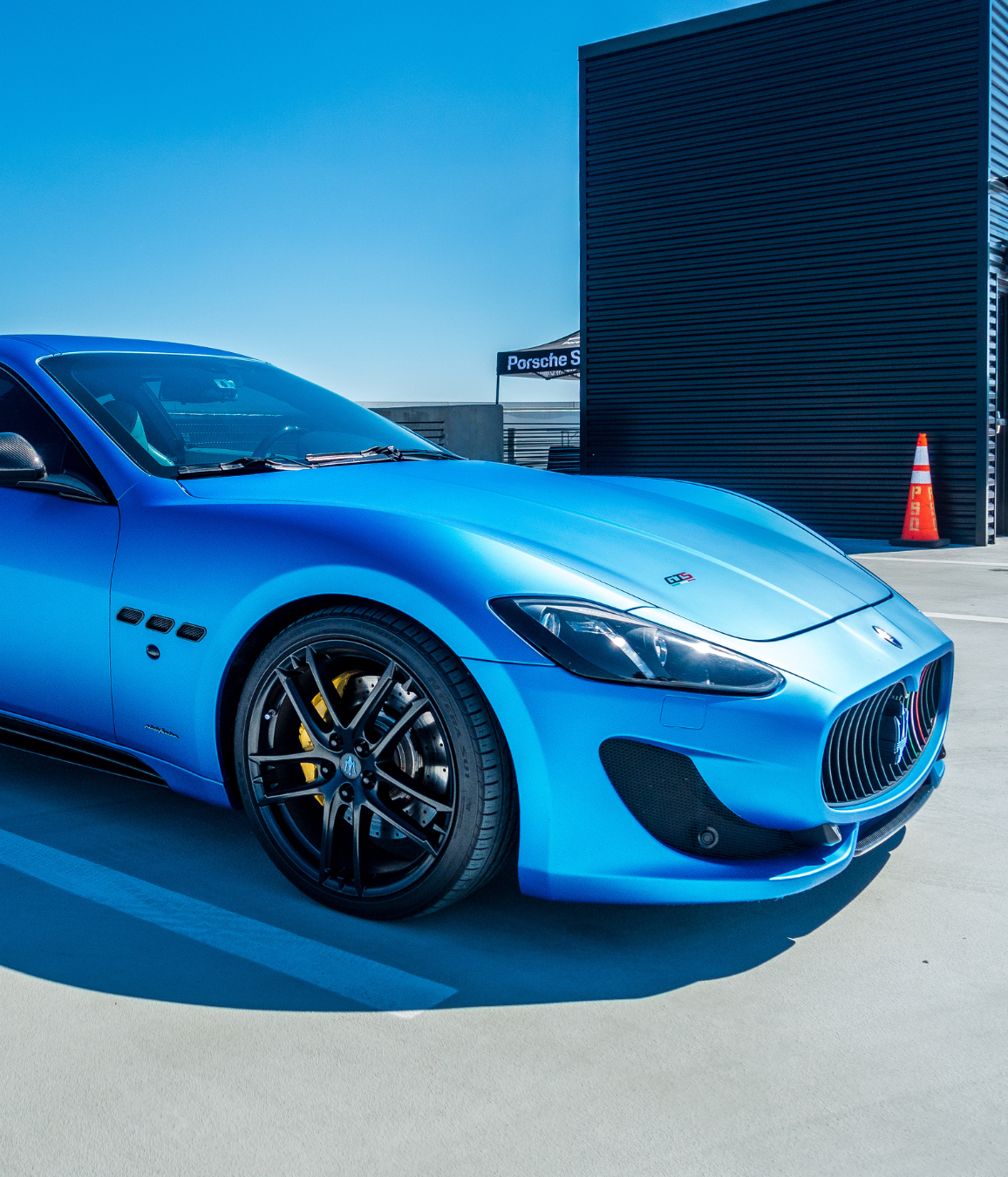 A blue sports car is parked in front of a building