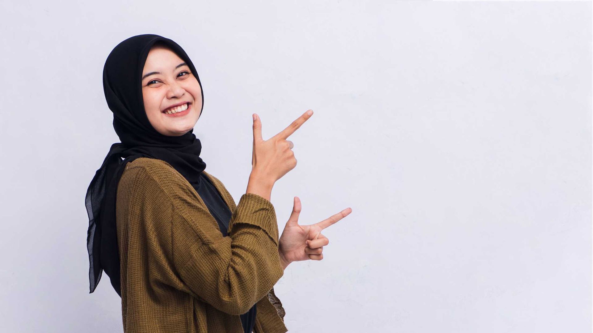 A woman in a hijab is pointing at something with her fingers.