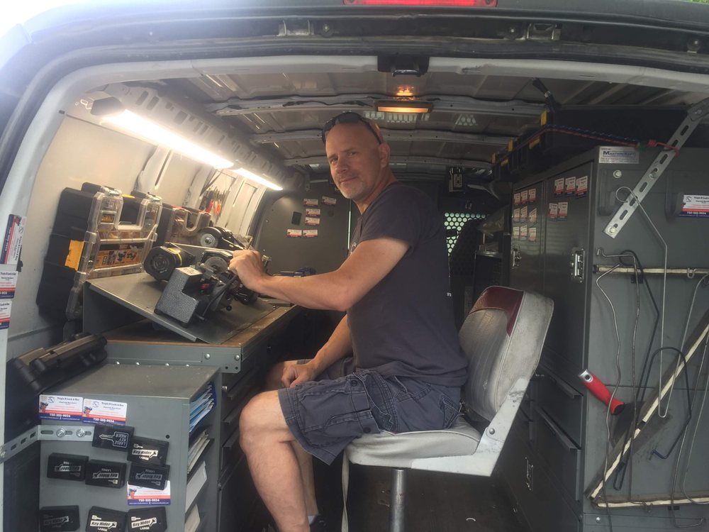 A man is sitting in the back of a van working on a machine