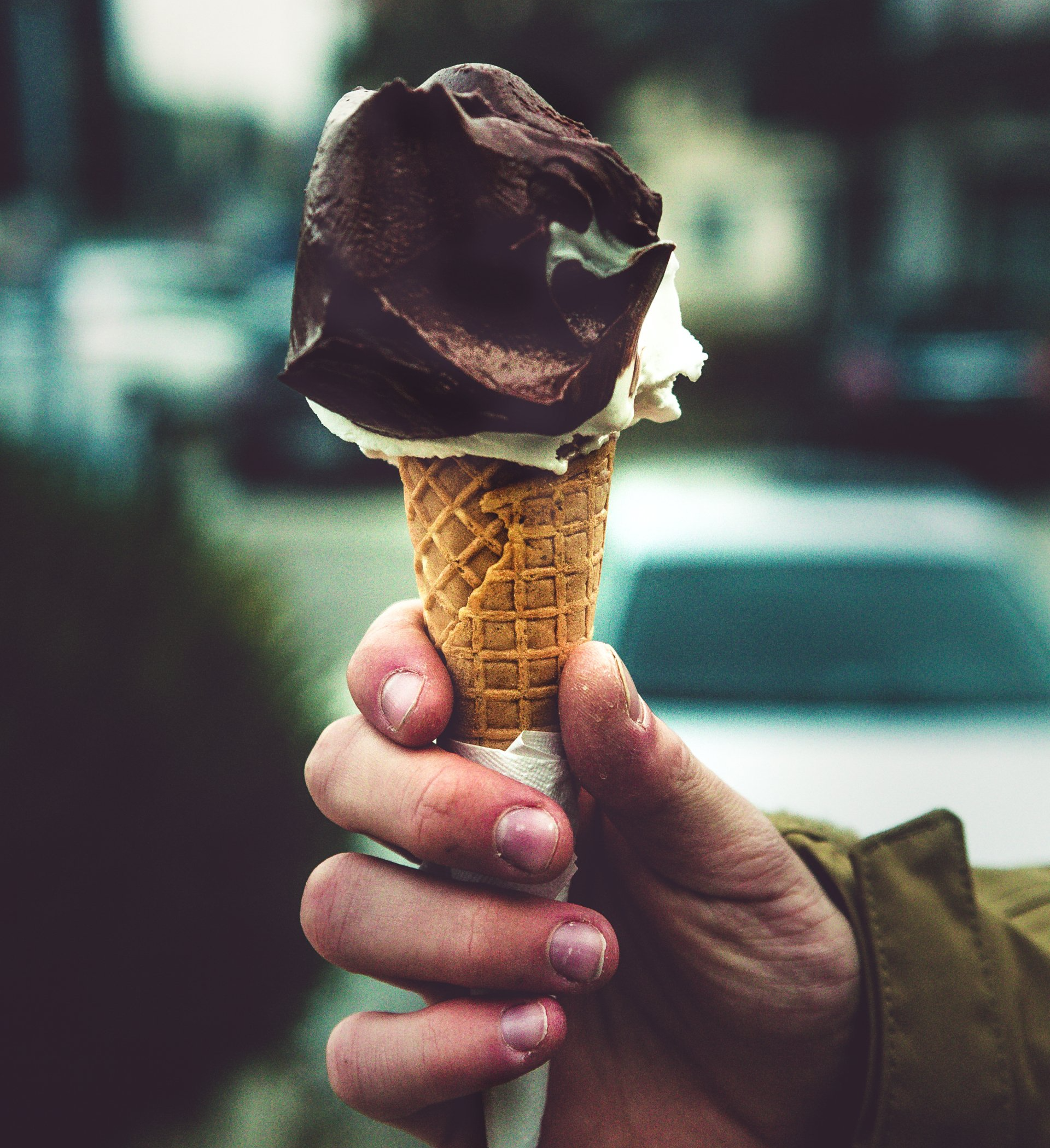Een hand met een ijsje met 1 bol en chocolade topping