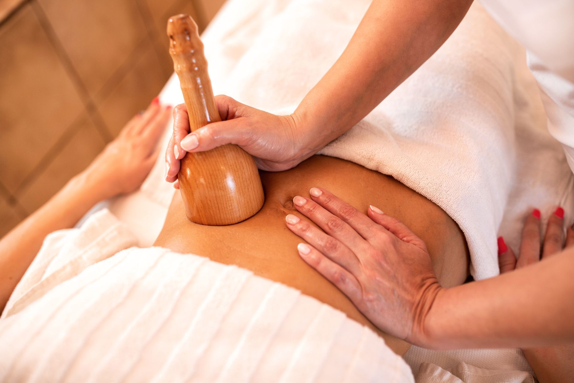 Lit candle, essential oil bottle, soap, and a cloth compress on a wooden surface for relaxation.