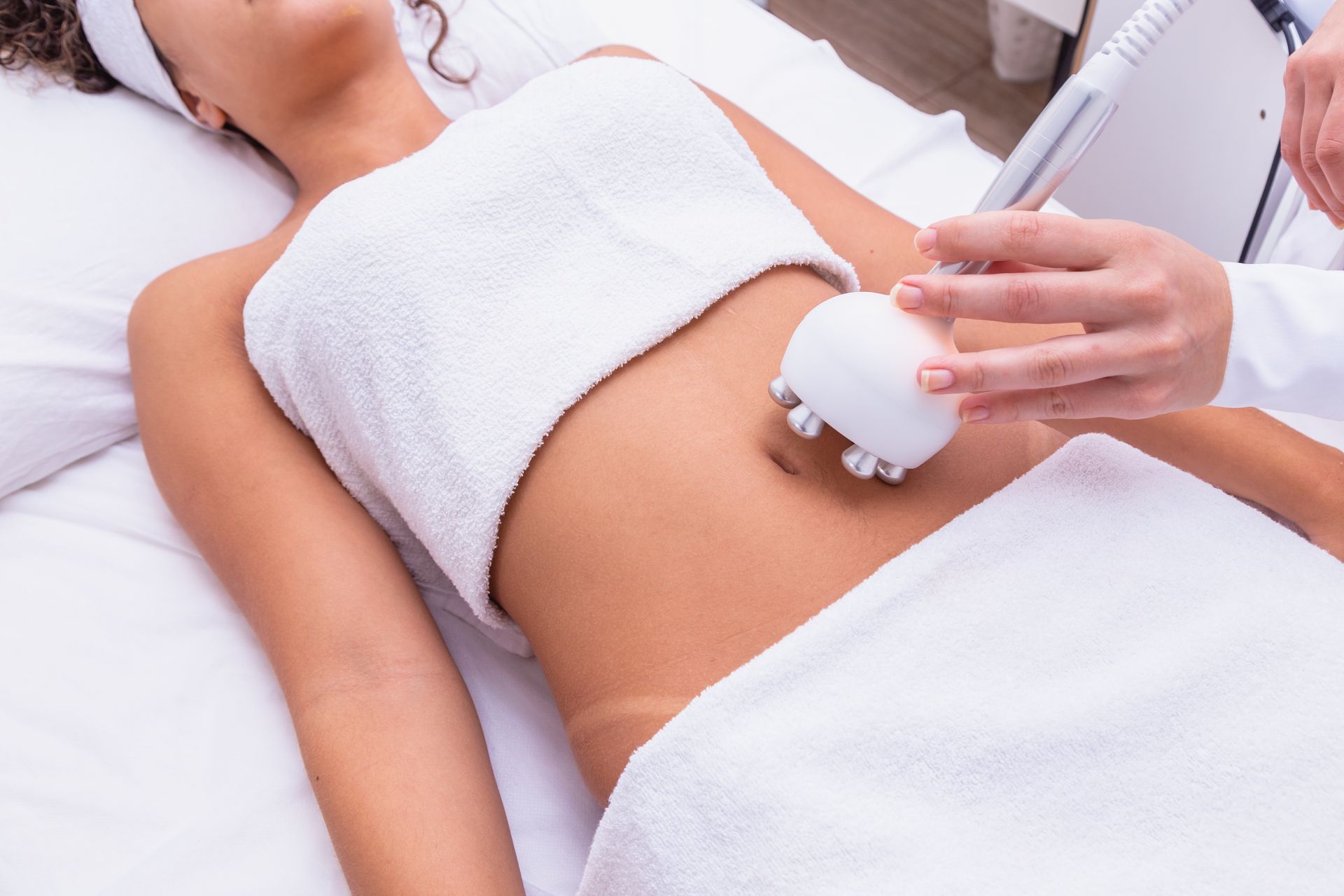 Woman receiving belly fat reduction treatment with a handheld device at a spa.