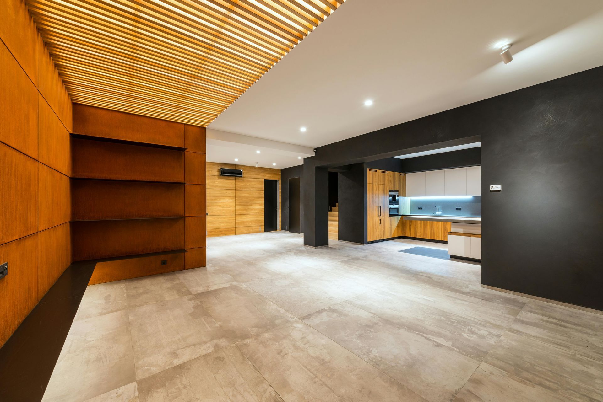 Empty modern interior with wood ceiling, black walls, and a light concrete floor
