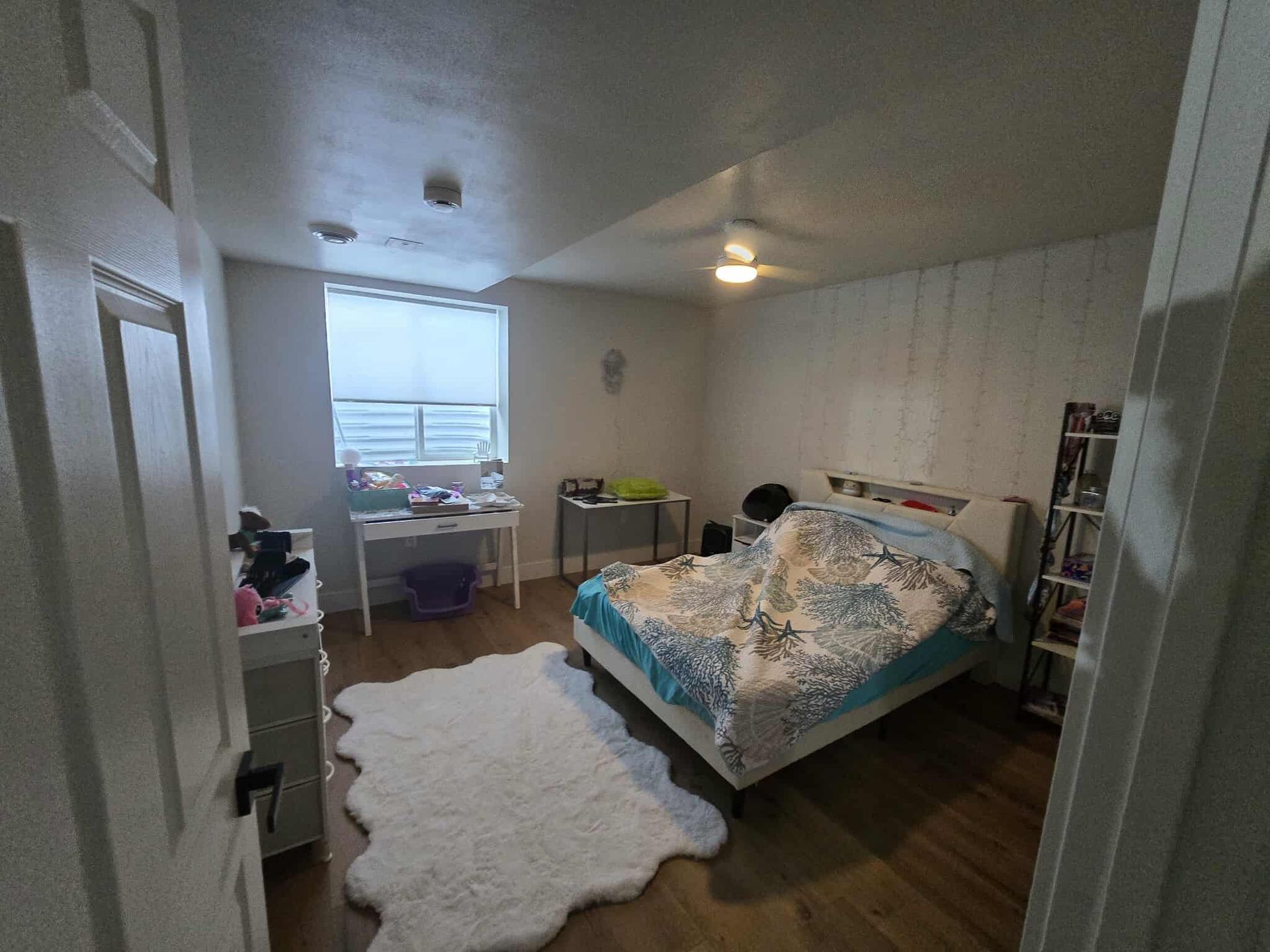 Bedroom with bed, desk, rug, and window.