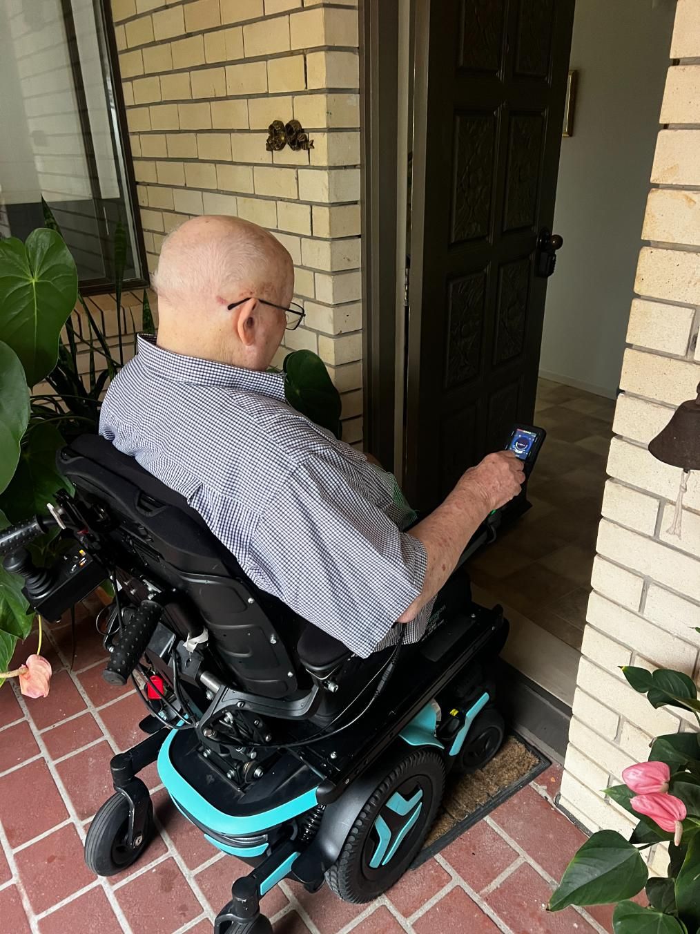 An occupational therapist is walking a woman in a wheelchair under an umbrella.
