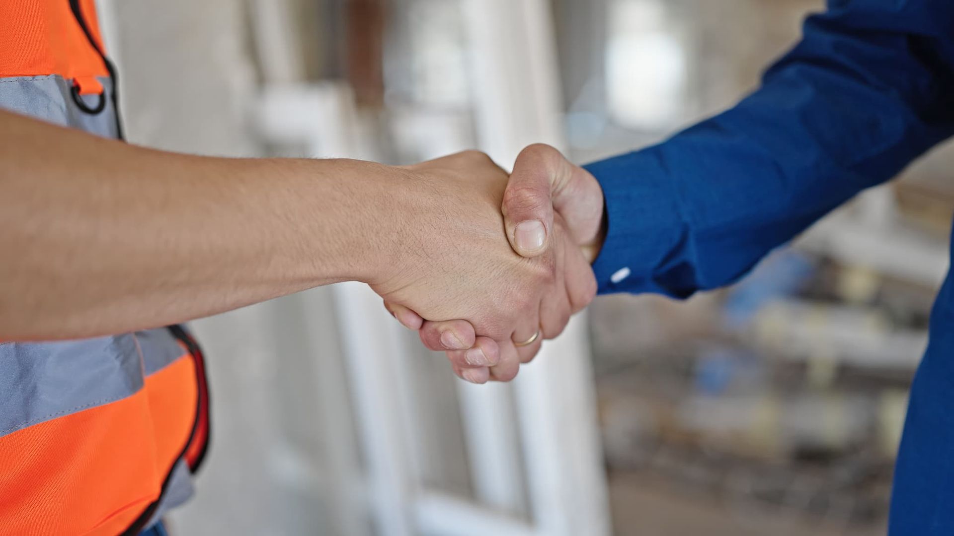 A man and a woman are shaking hands on a construction site.